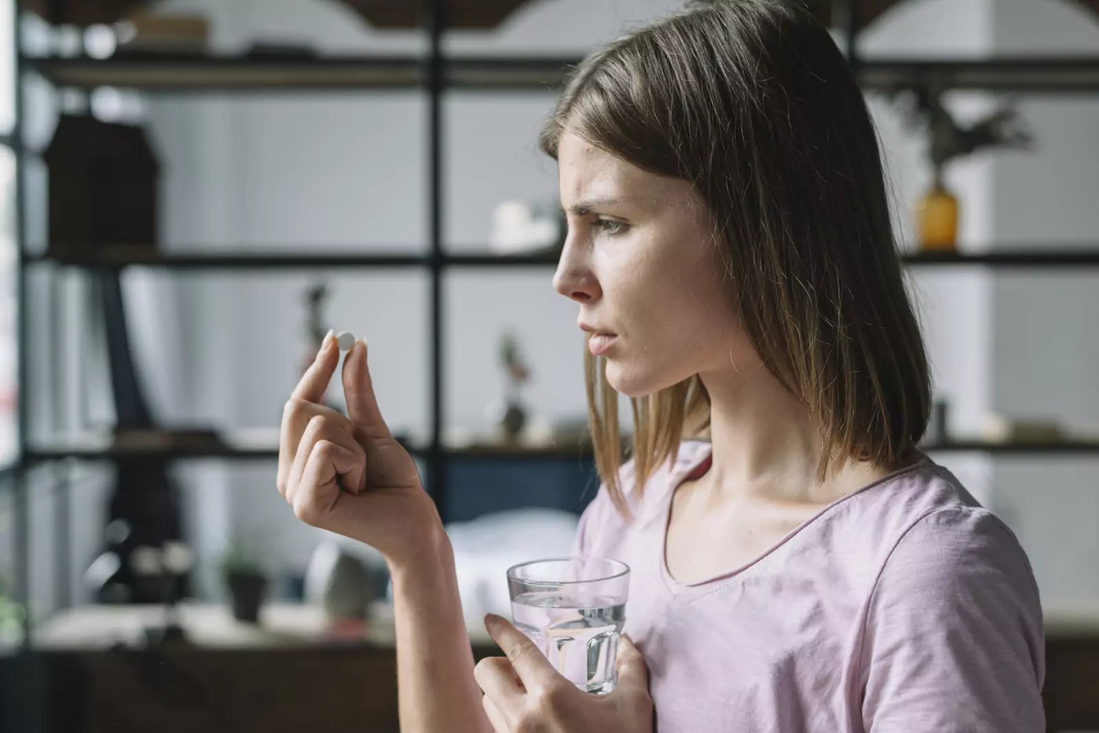 Sick Young Woman Looking Pill